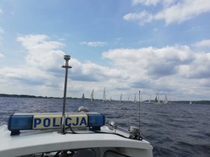 Policjanci za pomocą łodzi służbowej zabezpieczają regaty Salamander Cup 2019. Na pierwszym planie widać policyjną  łódź a w oddali jachty uczestniczące w regatach