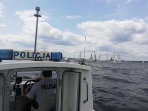 Policjanci za pomocą łodzi służbowej zabezpieczają regaty Salamander Cup 2019. Na pierwszym planie widać policyjną  łódź a w oddali jachty uczestniczące w regatach