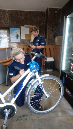 policjantka znakuje rower a dzielnicowy sprawdza czy nie był kradziony