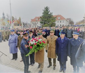 delegacje służb mundurowych składają kwiaty pod pomnikiem na Placu Wolności